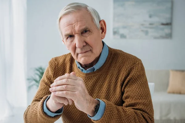 Senior thoughtful man sitting by the desk in light room — Stock Photo
