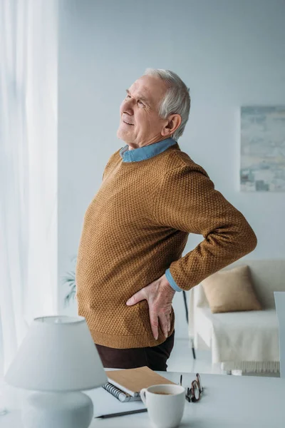 Hombre mayor que trabaja en la oficina sufriendo de dolor de espalda - foto de stock