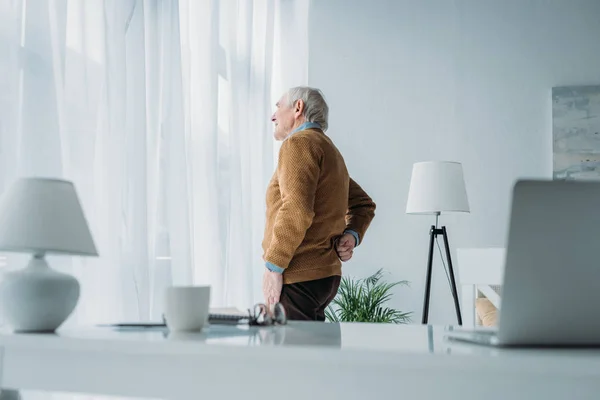 Homme âgé travaillant au bureau souffrant de maux de dos — Photo de stock