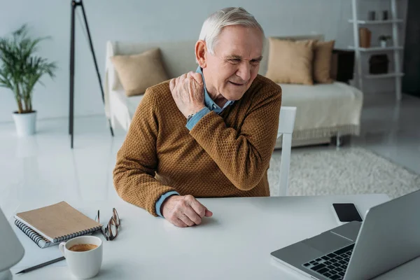 Uomo anziano che lavora su laptop che soffre di mal di schiena — Foto stock