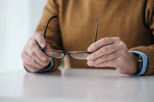 Close-up view of senior man holding eyeglasses — Stock Photo