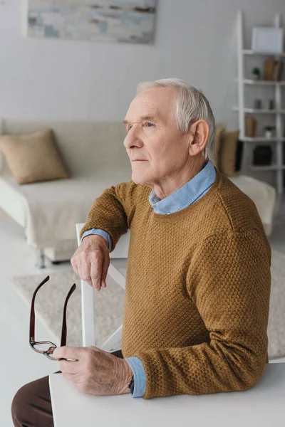 Senior nachdenklicher Mann sitzt am Schreibtisch in hellen Raum — Stockfoto