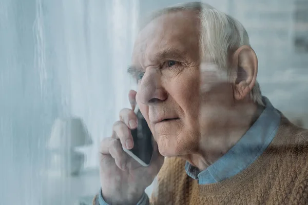 За скляним видом старшого тривожного чоловіка роблять телефонний дзвінок — Stock Photo