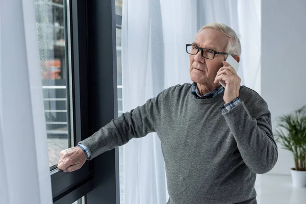 Hombre mayor confiado en anteojos haciendo una llamada telefónica - foto de stock