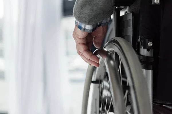 Vue rapprochée de l'homme âgé main sur roue de fauteuil roulant — Photo de stock