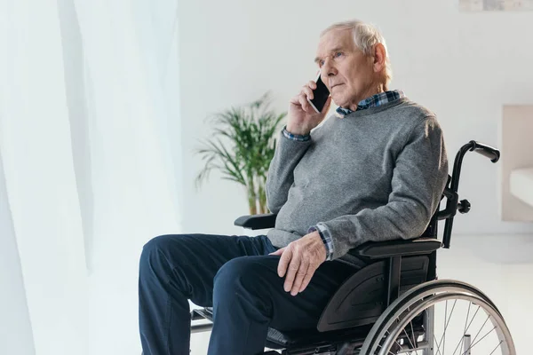 Старший чоловік у візку робить телефонний дзвінок у порожній кімнаті — стокове фото