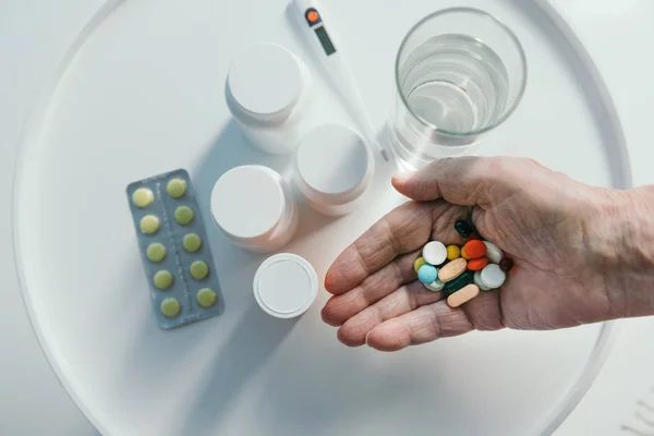 Vista de cerca de la mano del hombre mayor sosteniendo un montón de pastillas - foto de stock