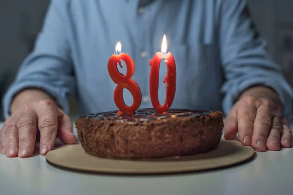 Vista de perto do homem sênior que celebra 80 anos com bolo e velas de número ardente — Fotografia de Stock