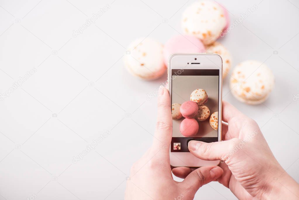 Hands photographing macarons