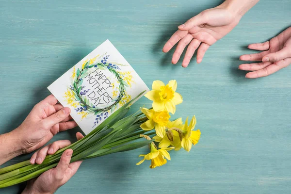 Hombre presentando tarjeta y narcisos - foto de stock