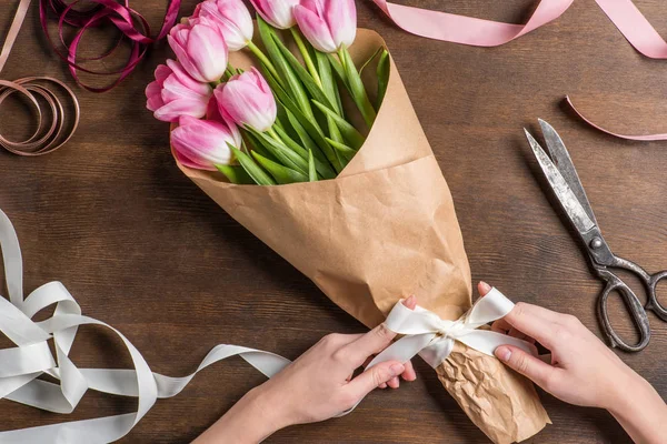 Рожеві тюльпани і руки з стрічкою — стокове фото