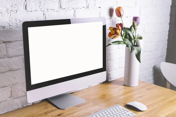 monitor and white vase with flowers