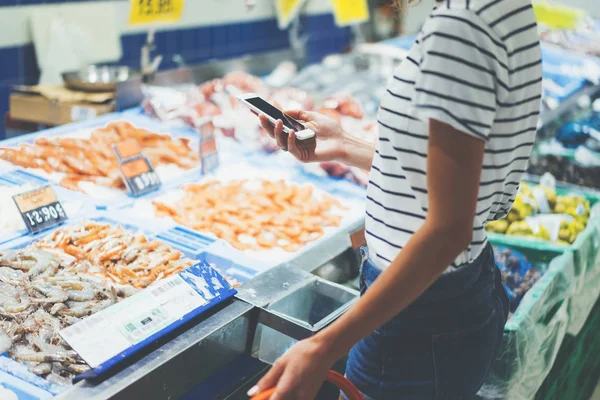 woman using smartphone in supermarket