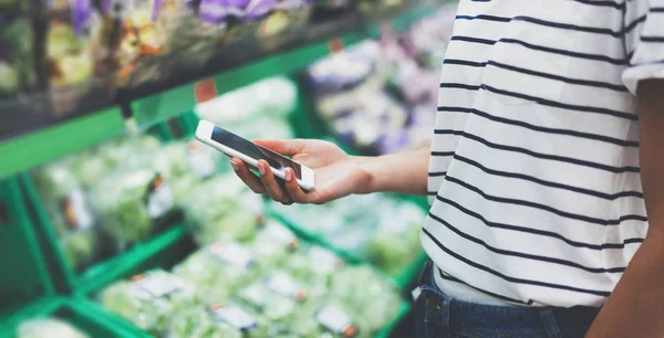 woman using smartphone in supermarket