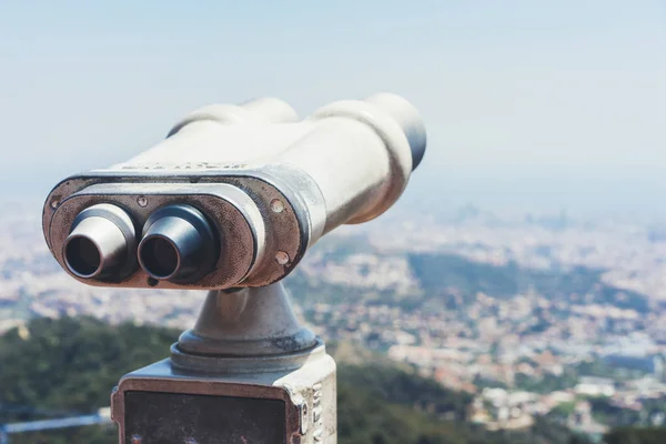 old metal binoculars overlooking cityscape