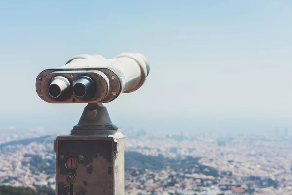 old metal binoculars overlooking cityscape