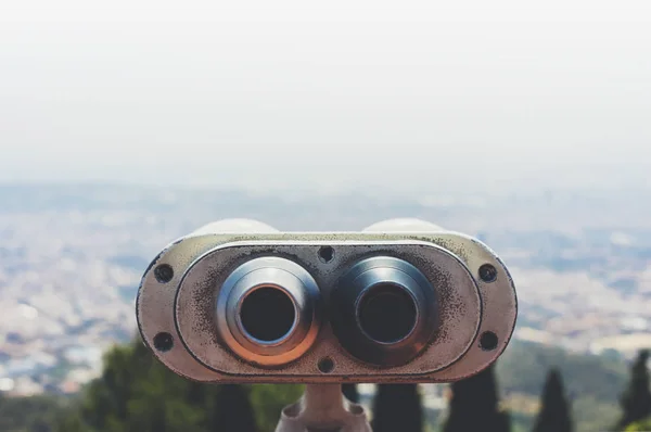 old metal binoculars overlooking cityscape