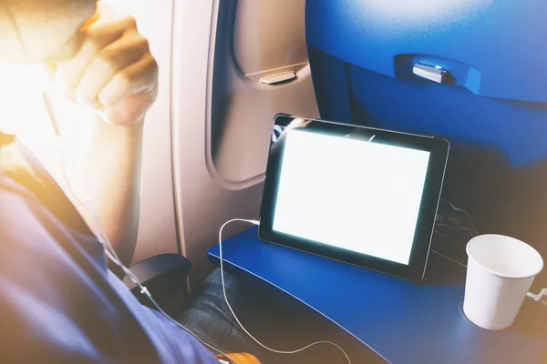 Side view of passenger traveler tourist using tablet at salon airplane. Female hands texting message on gadget on background window aircraft, summer traveler journey trip concept, mockup blank screen computer with flare