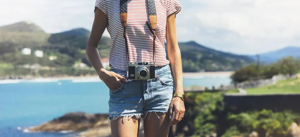 Tourist traveler photographer making pictures sea scape on vintage photo camera on background ocean, hipster girl enjoying peak mountain and nature holiday, mock up ocean waves view, blurred backdrop