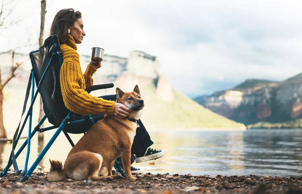 tourist traveler girl relax drink tea together dog on background mountain, puppy pet woman think on lake shore nature trip, friendship concept