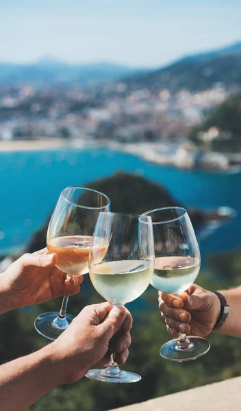 Drink  glasses white wine in friends hands outdoor seascape holidays, happy people cheering fun vacation enjoying travel time together friendship concept congratulations