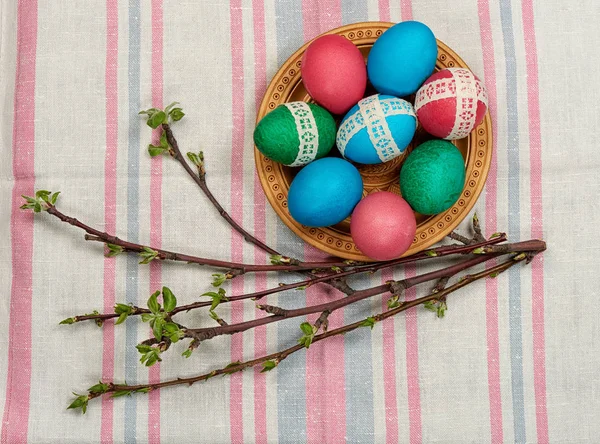 Huevos de Pascua en plato de madera en la toalla — Foto de Stock