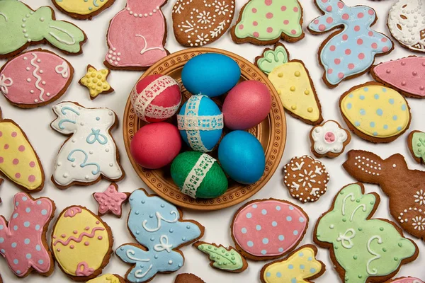 Huevos de pascua en plato de madera y pan de jengibre de pascua — Foto de Stock