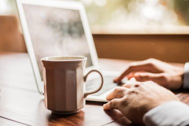 Bir fincan çay ve dizüstü bilgisayarlı bir işyeri. 