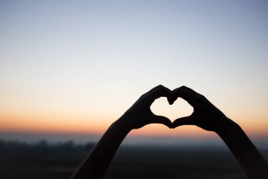 Elleriyle kalp şeklinde bir siluet.