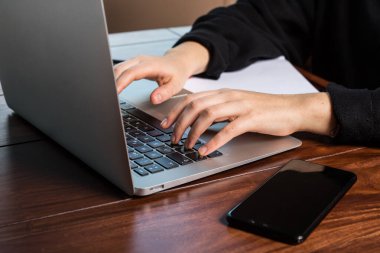 Dizüstü bilgisayarın klavyesini kullanan eller.