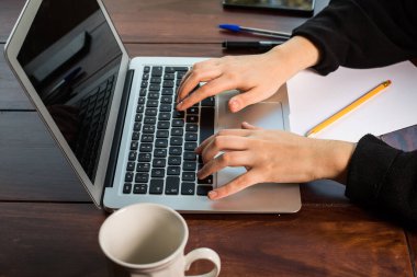 Dizüstü bilgisayarın klavyesini kullanan eller.