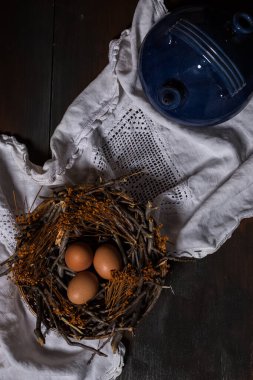 Bir yuvada üç yumurta ve bir mavi toprak kaplama sürahisi.