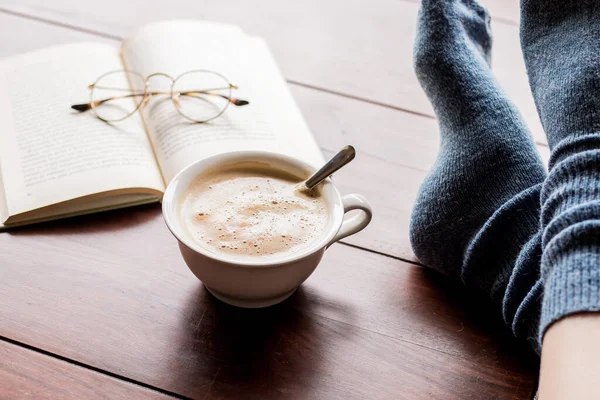Tasse Kaffee Und Ein Buch Mit Füßen Auf Einem Tisch — Stockfoto