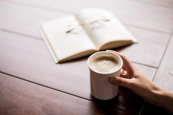 Eine Hand Nimmt Eine Tasse Kaffee Hintergrund Ein Buch Und — Stockfoto