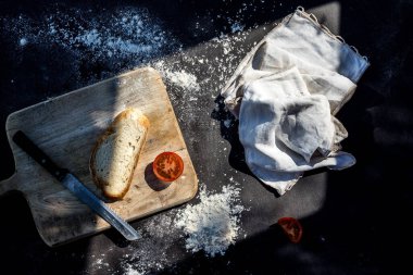 Bir parça ekmek ve domatesli siyah yemek masası.