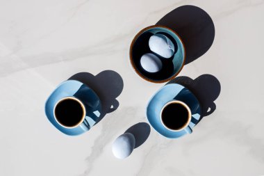 Beyaz arkaplanlı bir fincan çay ve mavi yumurta.