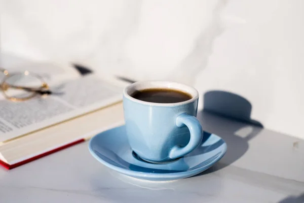 cup of coffee and book with glasses on it
