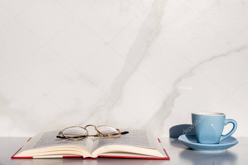 cup of coffee and book with glasses on it