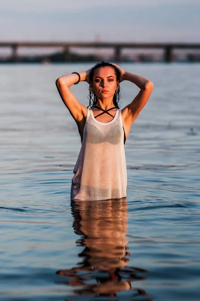 Meisje spetteren in het water geconfronteerd met de zonsondergang — Stockfoto
