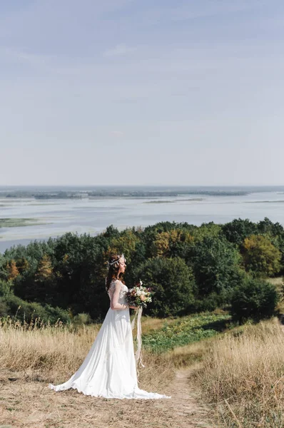 Die Braut in einem weißen Kleid auf dem Gipfel des Berges zum Fluss verschüttet — Stockfoto