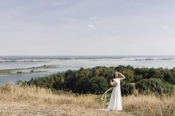 Nevěsta v bílých šatech na vrcholu hory k rozlití řeky — Stock fotografie