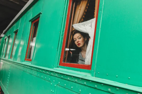 A menina olha para uma velha janela de carruagem ferroviária — Fotografia de Stock