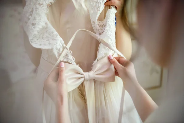 Bride straightens a bow on a wedding dress — Stock Photo, Image