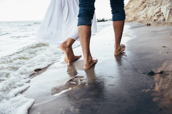 Um casal apaixonado andando descalço na areia molhada na praia i — Fotografia de Stock
