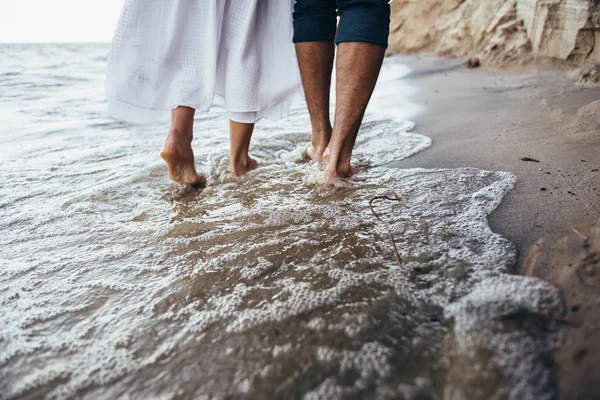 Una pareja enamorada caminando descalza sobre la arena mojada en la playa i — Foto de Stock