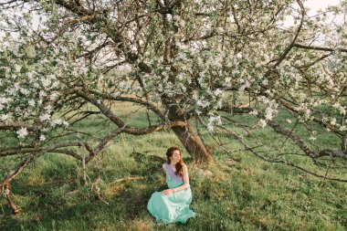 Bir çiçekli elma bahçesi bahar bir kız cro altında oturur
