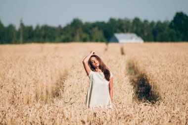 Bir buğday alan ortasında beyaz elbiseli bir kız