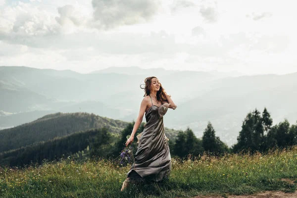 Una bella ragazza in un vestito e un mazzo di fiori in mano — Foto Stock