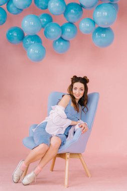 pembe odasındabir kızla tavanda mavi bir koltuğa oturur th