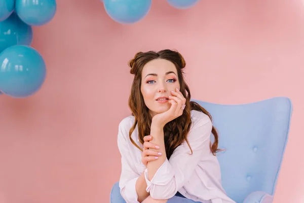 Uma menina em um quarto rosa senta-se em uma poltrona azul e olha para o c — Fotografia de Stock